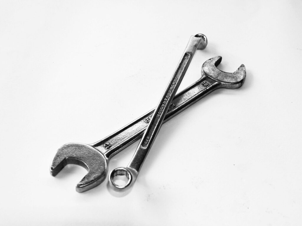 A pair of crossed metal wrenches on a clean white surface.